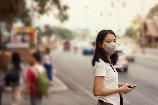 asian girl on street and wearing pm 2.5 mask for safety from air pollution