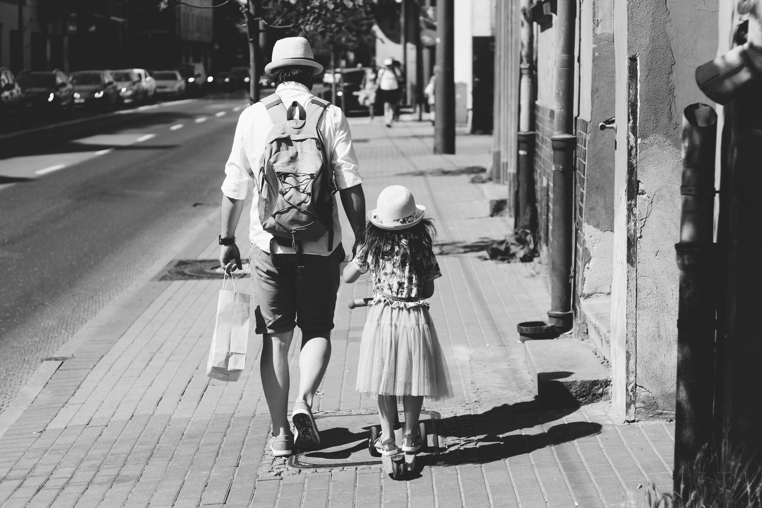 man-holding-girl-while-walking-on-street-1194209